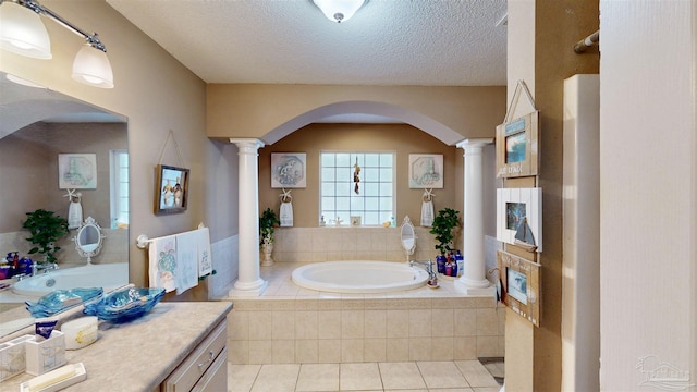 bathroom featuring decorative columns, vanity, a textured ceiling, and a bath