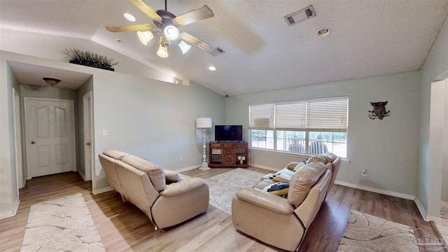 living room featuring light wood finished floors, ceiling fan, visible vents, and vaulted ceiling