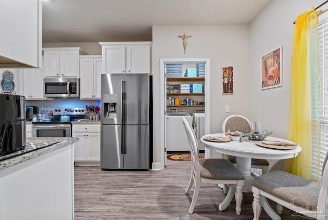 5323 Red Shoulder Rd, Pace, FL 32571 - kitchen with appliances with stainless steel finishes, washer and dryer, light wood finished floors, and white cabinetry