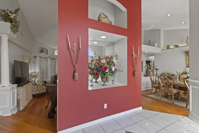 entryway with a towering ceiling, decorative columns, and light tile patterned floors