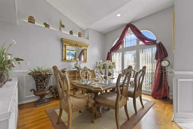 dining room with lofted ceiling, a textured ceiling, and light hardwood / wood-style flooring