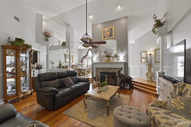 living room featuring decorative columns, wood-type flooring, high vaulted ceiling, and ceiling fan