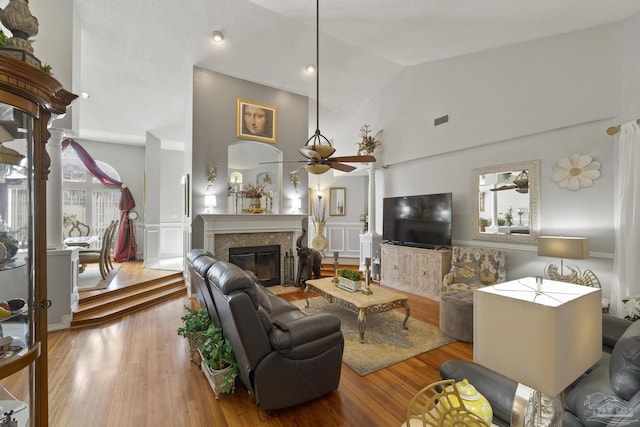 living room featuring ceiling fan, high vaulted ceiling, a high end fireplace, and light hardwood / wood-style flooring