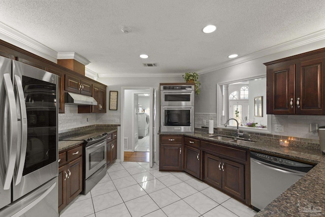 kitchen featuring ornamental molding, appliances with stainless steel finishes, sink, and dark stone countertops