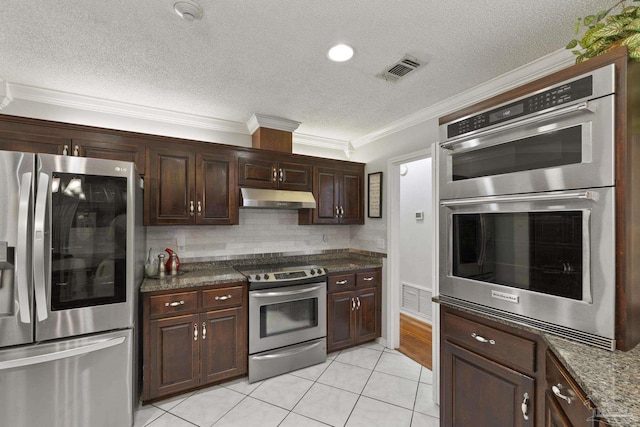 kitchen with tasteful backsplash, dark stone countertops, ornamental molding, dark brown cabinetry, and stainless steel appliances