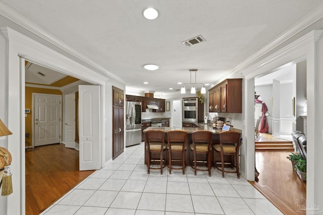 kitchen featuring crown molding, light tile patterned floors, decorative backsplash, and appliances with stainless steel finishes