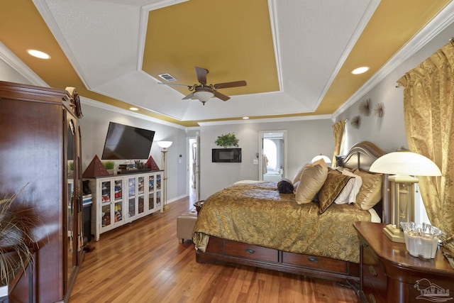 bedroom featuring crown molding, hardwood / wood-style floors, ceiling fan, and a tray ceiling