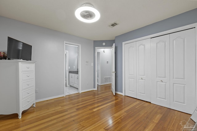 unfurnished bedroom featuring ensuite bath, light hardwood / wood-style floors, and a closet