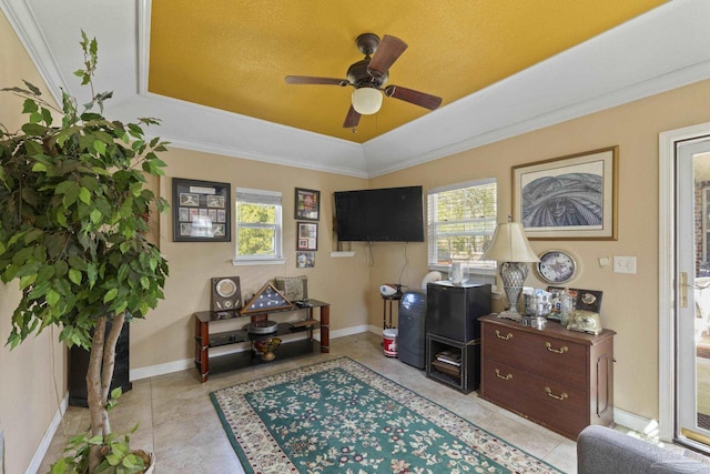 interior space with light tile patterned flooring, ceiling fan, crown molding, and a raised ceiling