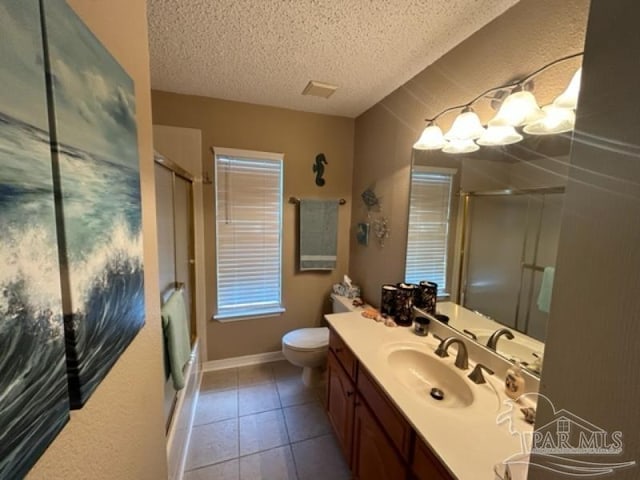 bathroom with vanity, toilet, tile patterned floors, and a textured ceiling