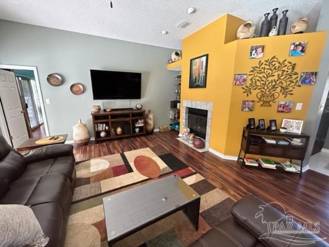 living room with dark hardwood / wood-style floors, a fireplace, and a textured ceiling