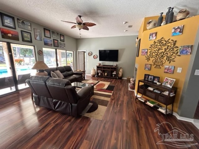 living room with ceiling fan, dark hardwood / wood-style flooring, and a textured ceiling