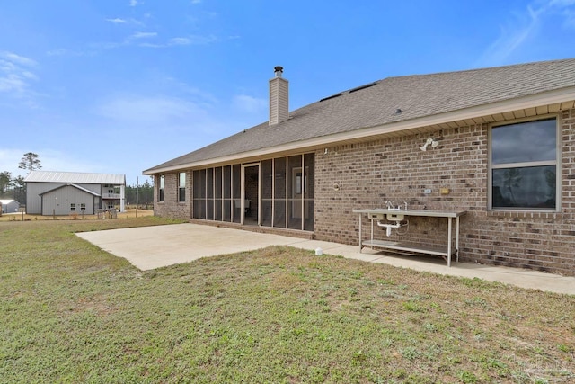 rear view of house featuring a yard, a sunroom, and a patio