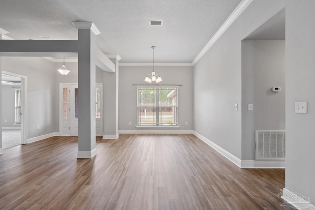 interior space featuring wood-type flooring, ornamental molding, a notable chandelier, and a textured ceiling