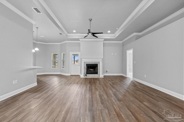 unfurnished living room featuring ceiling fan, wood-type flooring, a tray ceiling, and a tile fireplace