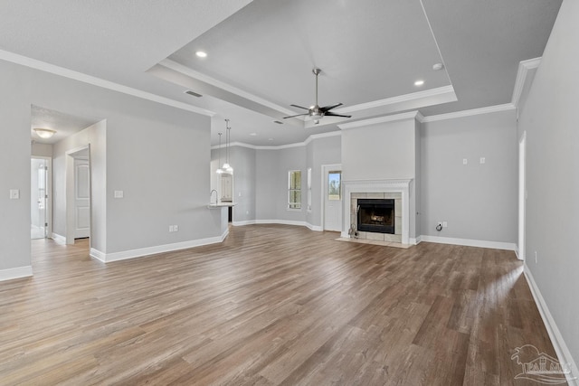 unfurnished living room with light hardwood / wood-style floors, a fireplace, and a tray ceiling