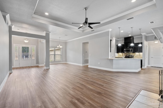 unfurnished living room with hardwood / wood-style flooring, a tray ceiling, ceiling fan with notable chandelier, and a textured ceiling