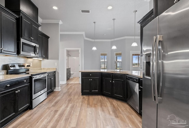 kitchen featuring pendant lighting, sink, light hardwood / wood-style flooring, appliances with stainless steel finishes, and decorative backsplash