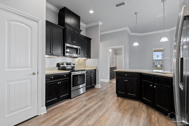 kitchen featuring appliances with stainless steel finishes, sink, backsplash, hanging light fixtures, and light wood-type flooring