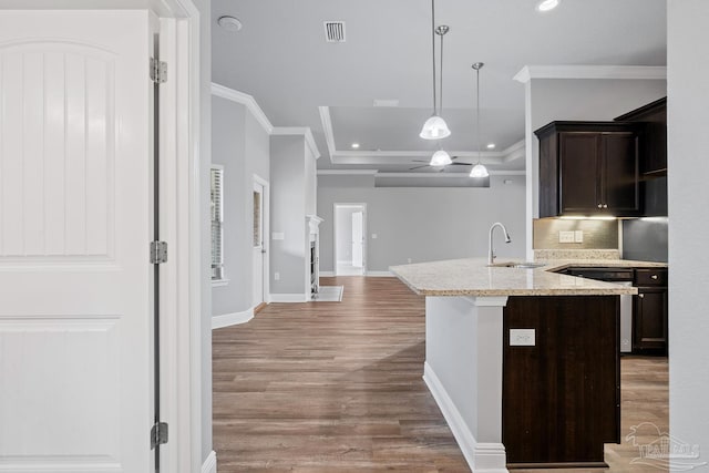 kitchen featuring sink, hanging light fixtures, light hardwood / wood-style floors, ornamental molding, and light stone countertops