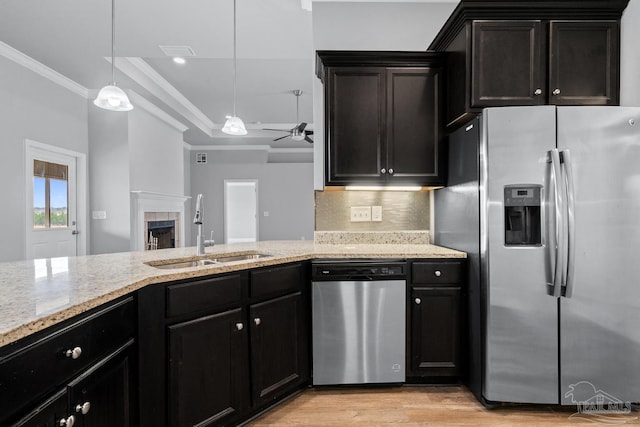 kitchen featuring sink, appliances with stainless steel finishes, ornamental molding, decorative light fixtures, and a raised ceiling