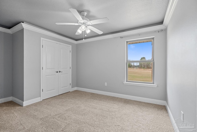 unfurnished bedroom with ceiling fan, crown molding, light carpet, a textured ceiling, and a closet