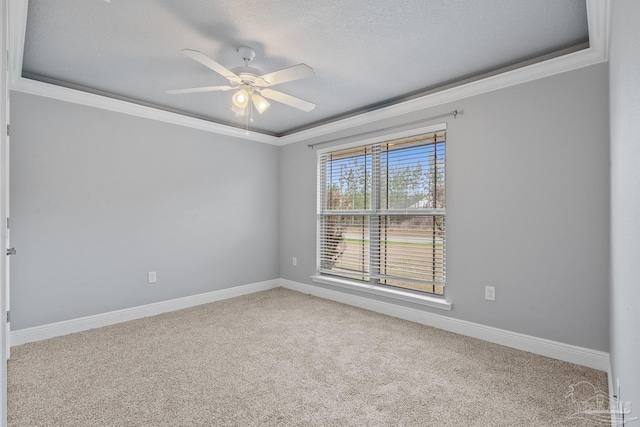 carpeted spare room featuring crown molding, a textured ceiling, ceiling fan, and a tray ceiling