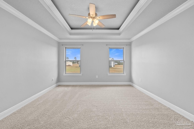 empty room featuring ceiling fan, carpet, ornamental molding, a textured ceiling, and a raised ceiling