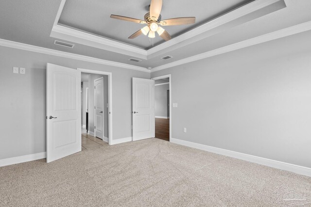 unfurnished bedroom with a raised ceiling, ornamental molding, light carpet, and ceiling fan