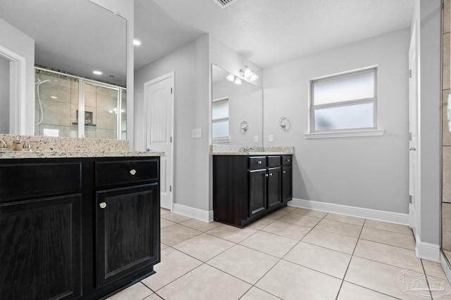 bathroom with tile patterned flooring, vanity, and a shower with door