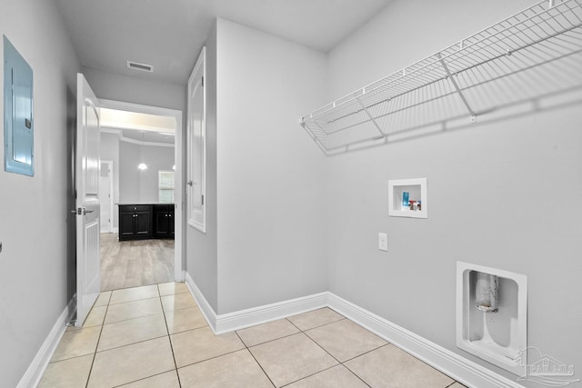 clothes washing area featuring electric panel, hookup for a washing machine, and light tile patterned floors