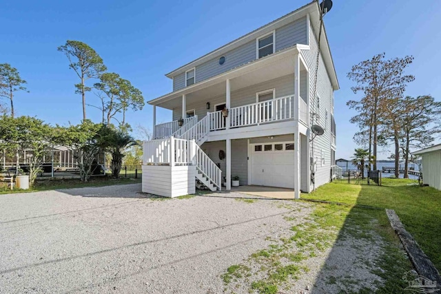 35868 Boykin Blvd, Lillian, AL 36549 - coastal inspired home featuring stairway, gravel driveway, covered porch, fence, and a front lawn