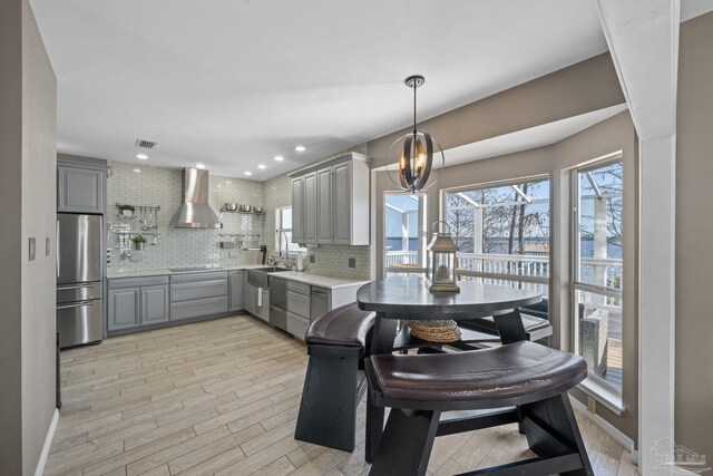 35868 Boykin Blvd, Lillian, AL 36549 - kitchen with light countertops, backsplash, gray cabinetry, appliances with stainless steel finishes, and wall chimney exhaust hood