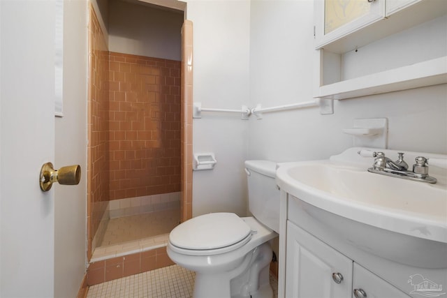 bathroom featuring toilet, tile patterned floors, tiled shower, and vanity