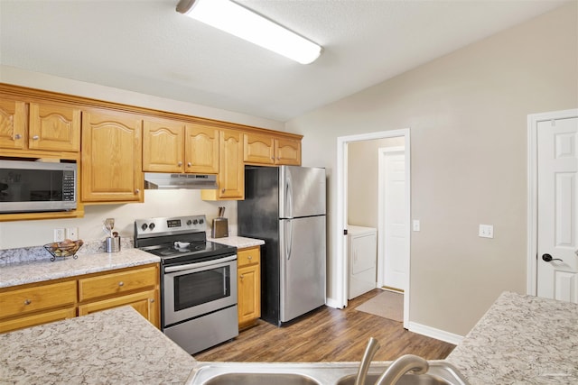 kitchen featuring washer / dryer, sink, stainless steel appliances, vaulted ceiling, and dark hardwood / wood-style floors