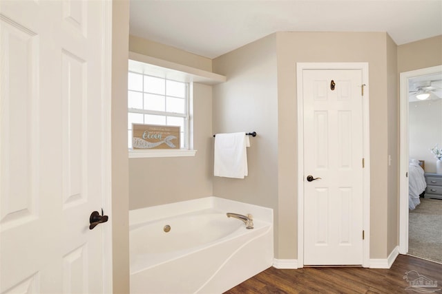 bathroom featuring hardwood / wood-style flooring, a tub to relax in, and ceiling fan