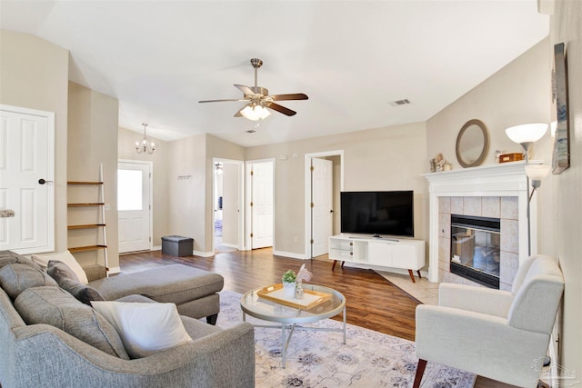 living room with ceiling fan with notable chandelier, wood-type flooring, lofted ceiling, and a fireplace