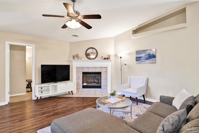 living room with lofted ceiling, a tiled fireplace, wood-type flooring, and ceiling fan