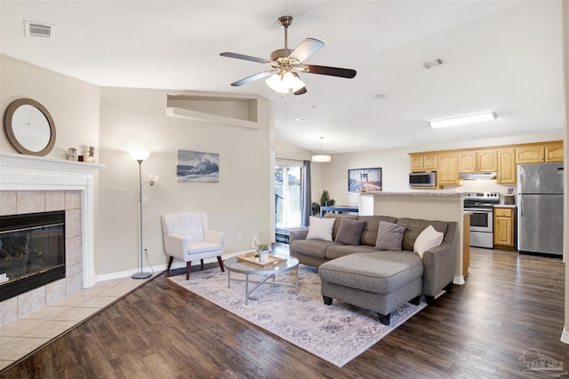 living room with lofted ceiling, ceiling fan, a tile fireplace, and dark hardwood / wood-style flooring