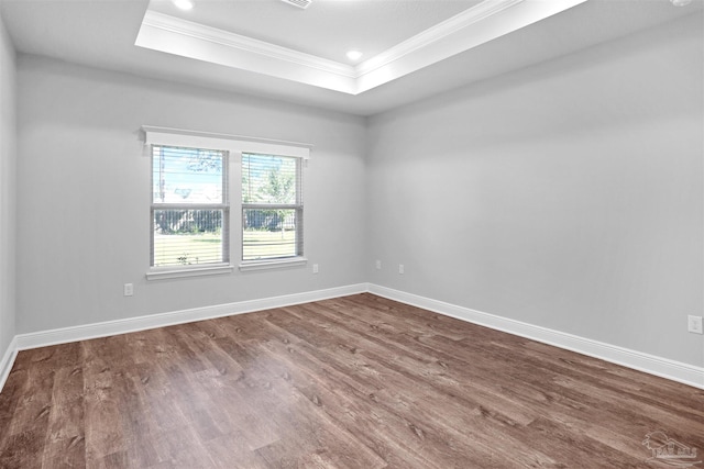 spare room with wood-type flooring, a raised ceiling, and crown molding