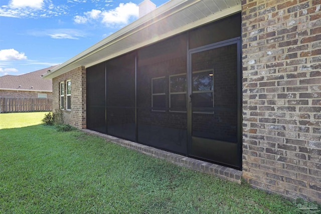 view of property exterior featuring a sunroom and a lawn