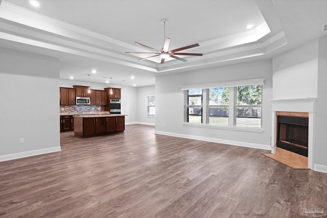 unfurnished living room featuring a raised ceiling, crown molding, dark hardwood / wood-style flooring, and ceiling fan