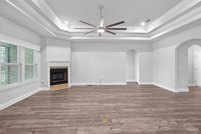 unfurnished living room with a tray ceiling, crown molding, dark hardwood / wood-style flooring, and a tiled fireplace