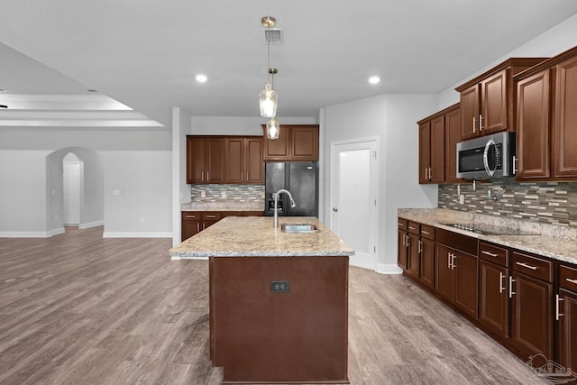 kitchen featuring tasteful backsplash, light hardwood / wood-style flooring, black appliances, and sink