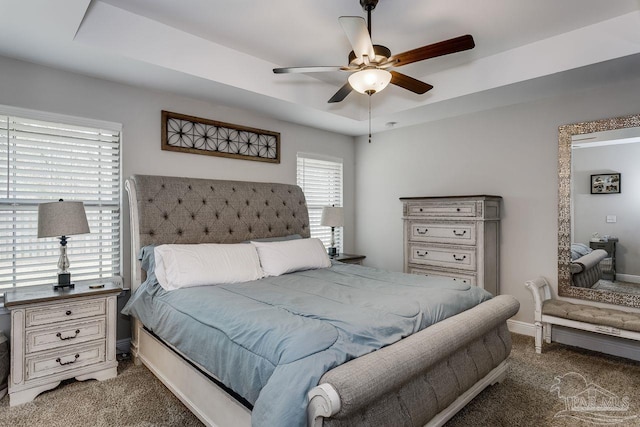 carpeted bedroom with a tray ceiling and ceiling fan