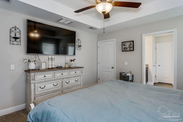 carpeted bedroom with a raised ceiling and ceiling fan