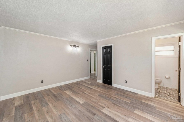 unfurnished bedroom with ornamental molding, ensuite bath, and hardwood / wood-style floors