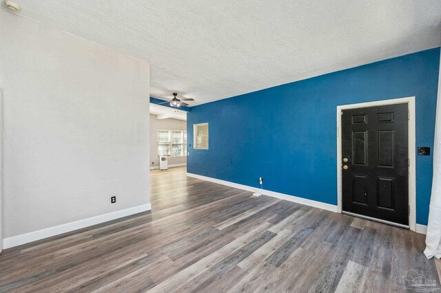 interior space with ceiling fan, a textured ceiling, and dark hardwood / wood-style floors