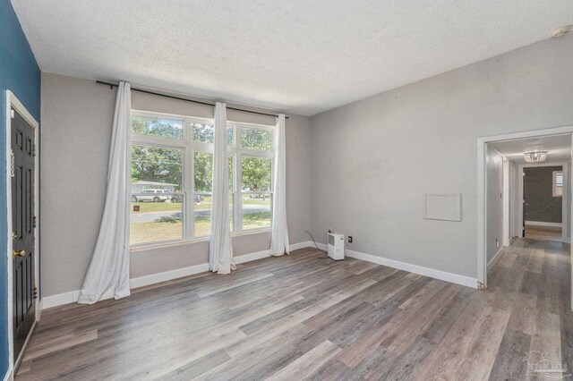 unfurnished room with a wealth of natural light, a textured ceiling, and hardwood / wood-style floors