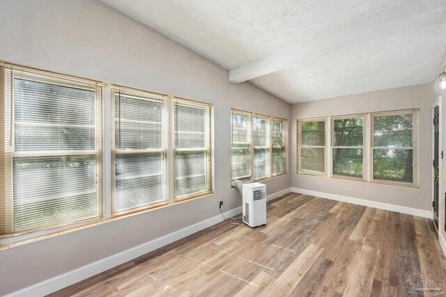 unfurnished sunroom featuring lofted ceiling with beams